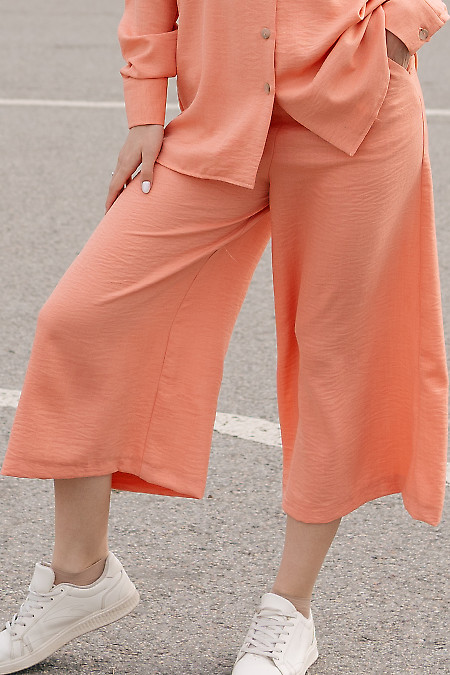 Штани-кюлоти коралового кольору. Діловий жіночий одяг фото